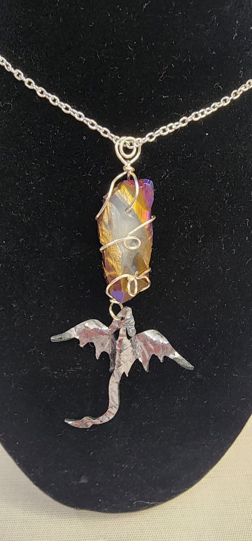 Necklace with a dragon pendant and multicolored gemstone on a black background